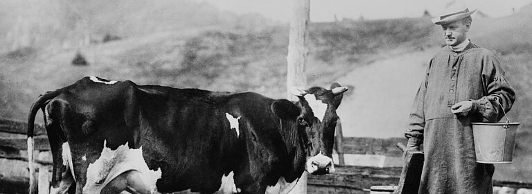 Schwarz-Weiß-Foto von einem Mann und einer Kuh