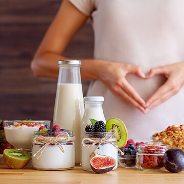 Abbildung Milchprodukte, im Hintergrund formt eine Person ein Herz mit ihren Händen