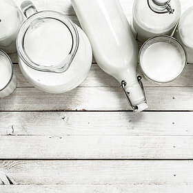 Milchkannen, -Flaschen und Gläser auf einem Holzuntergrund